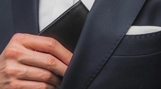 Man taking out a black wallet from a suit inner pocket